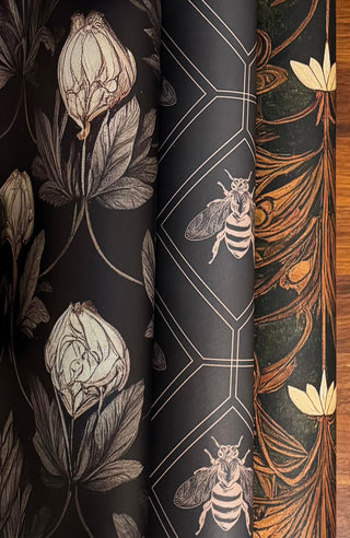 Rolled sheets of floral vintage drawer liners featuring bees and botanical patterns in deep tones.