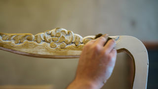 Close up view of hand applying wax finish to antique dining room chair