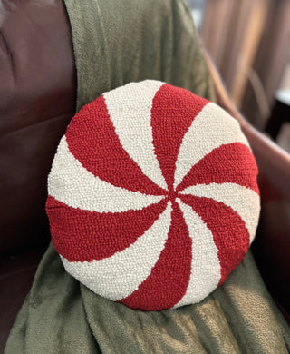 Soft wool holiday pillow with bold red and white swirl pattern on a leather chair