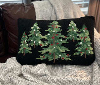 Hand-hooked wool holiday pillow featuring a forest of evergreen trees on a black background.